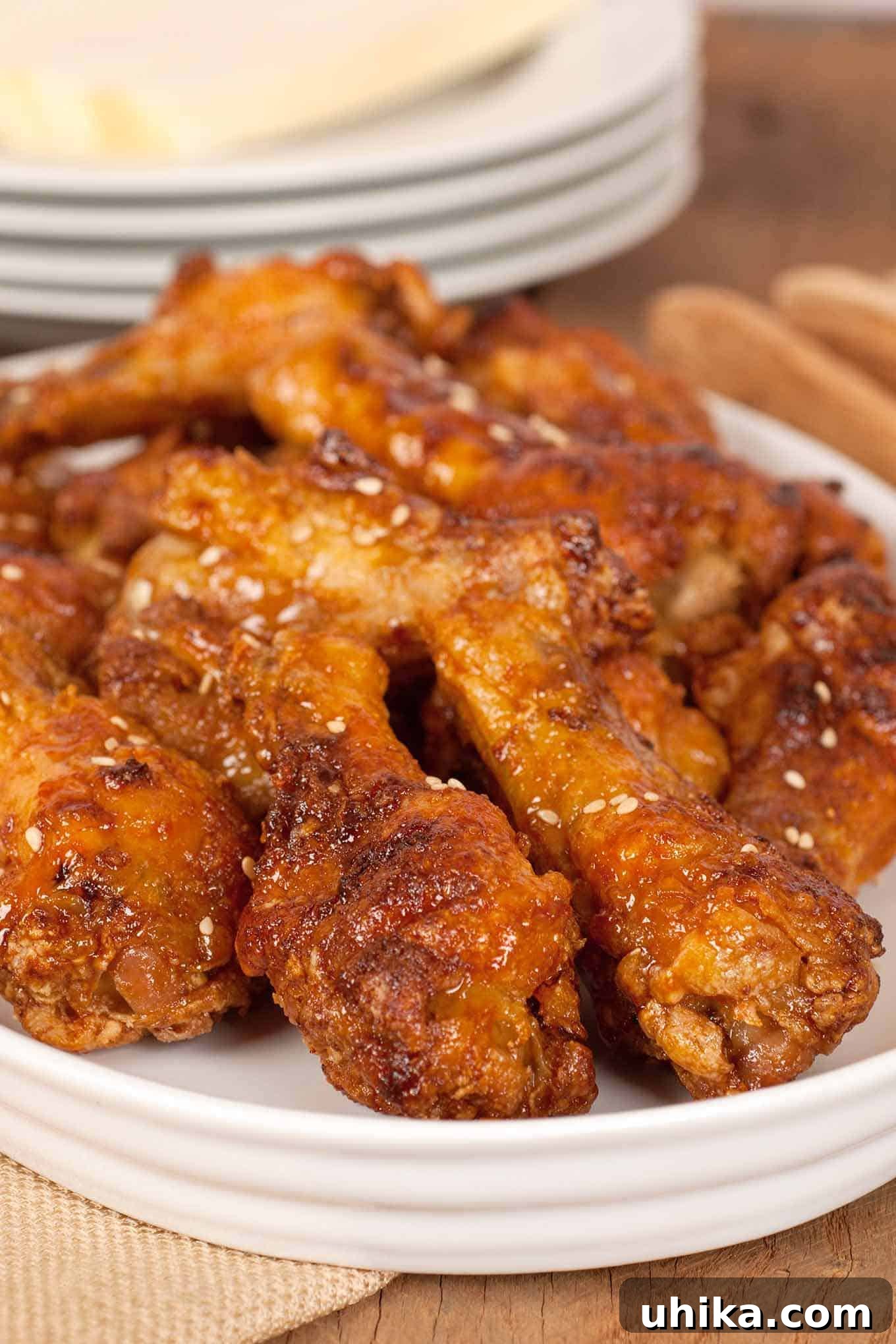 Crispy Baked Chicken Drumettes 2 Crispy oven-baked chicken wing drumettes with a vibrant citrus-soy glaze, garnished with sesame seeds, presented on a pristine white serving platter.