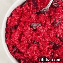 Roasted beet risotto in a white bowl, featuring creamy rice with vibrant red color and chunks of tender beet.