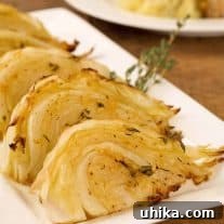 Close-up of golden brown roasted cabbage wedges with fresh thyme garnish.