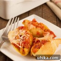 Savory Stuffed Sausage Shells 3 Sausage stuffed pasta shells topped with marinara and melted cheese, served on a white plate with a fork.