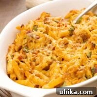 Baked barbecue chicken pasta in a white casserole dish, topped with melted cheese.
