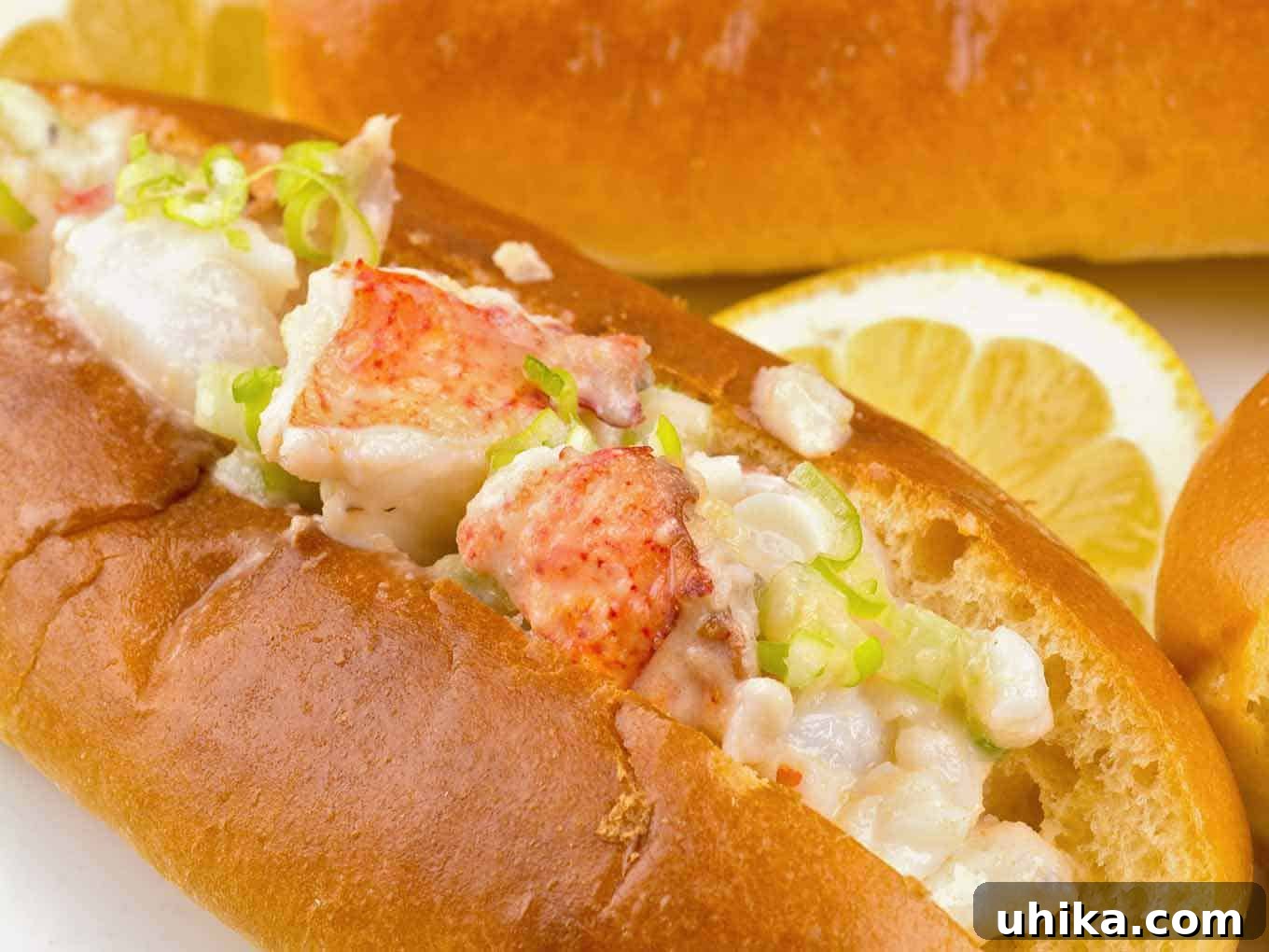 Atlantic Lobster Bliss 3 A close up of a single New England lobster roll, garnished with a lemon wedge.