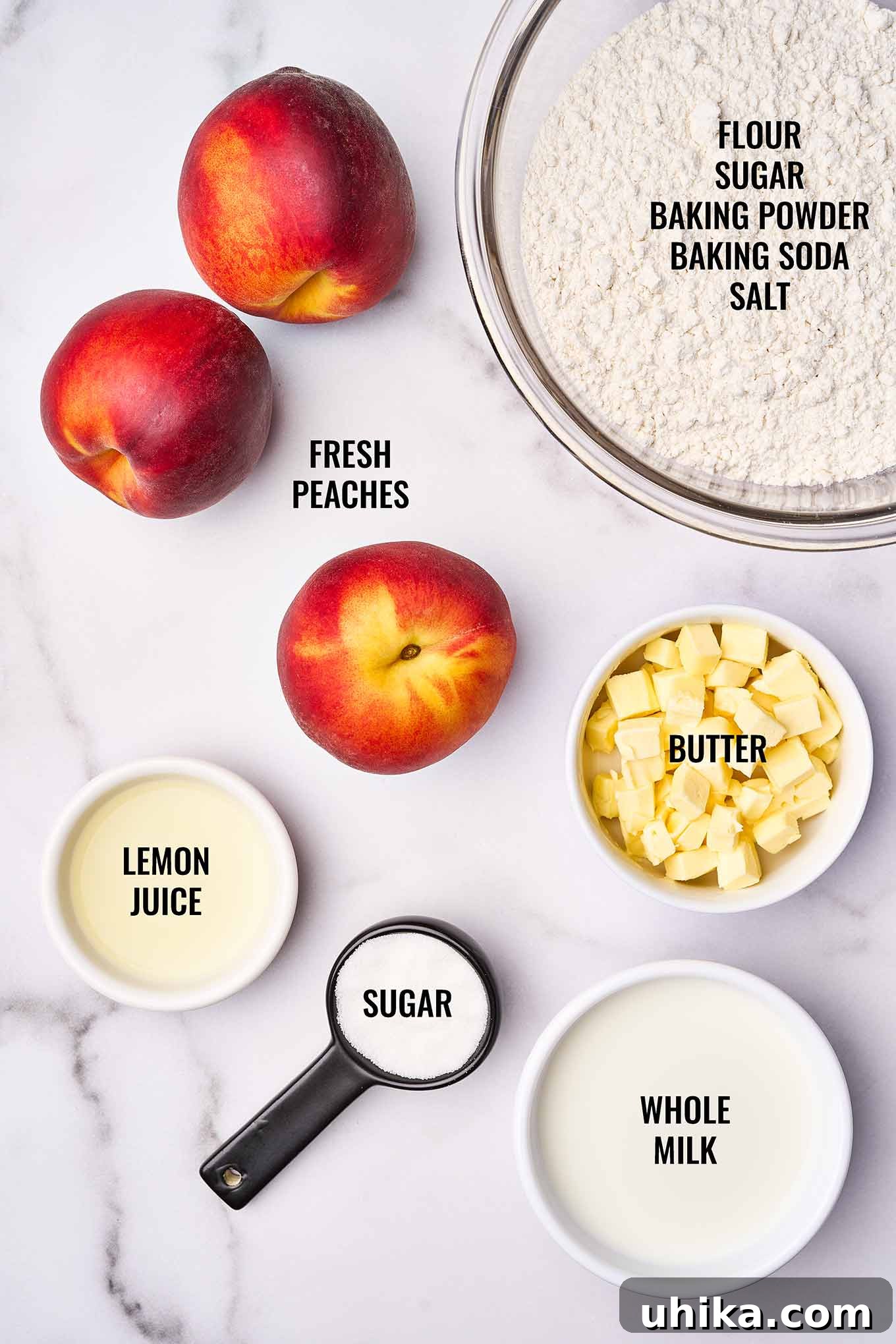 Summertime Fresh Peach Cobbler 3 Overhead view of labeled peach cobbler ingredients including whole peaches, lemon juice, sugar, butter, milk, flour, baking soda, baking powder, and salt.