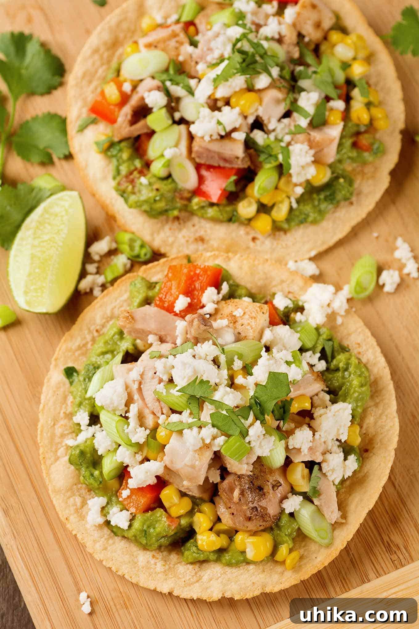 Crispy Roasted Chicken Tostadas 2 An overhead view of oven-crisped corn tortillas, topped with guacamole, roasted chicken, corn, red bell pepper and crumbled queso fresco cheese. A truly irresistible and easy Mexican dinner.