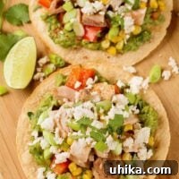 An overhead view of oven-crisped corn tortillas, topped with guacamole, roasted chicken, corn, red bell pepper and crumbled queso fresco cheese.