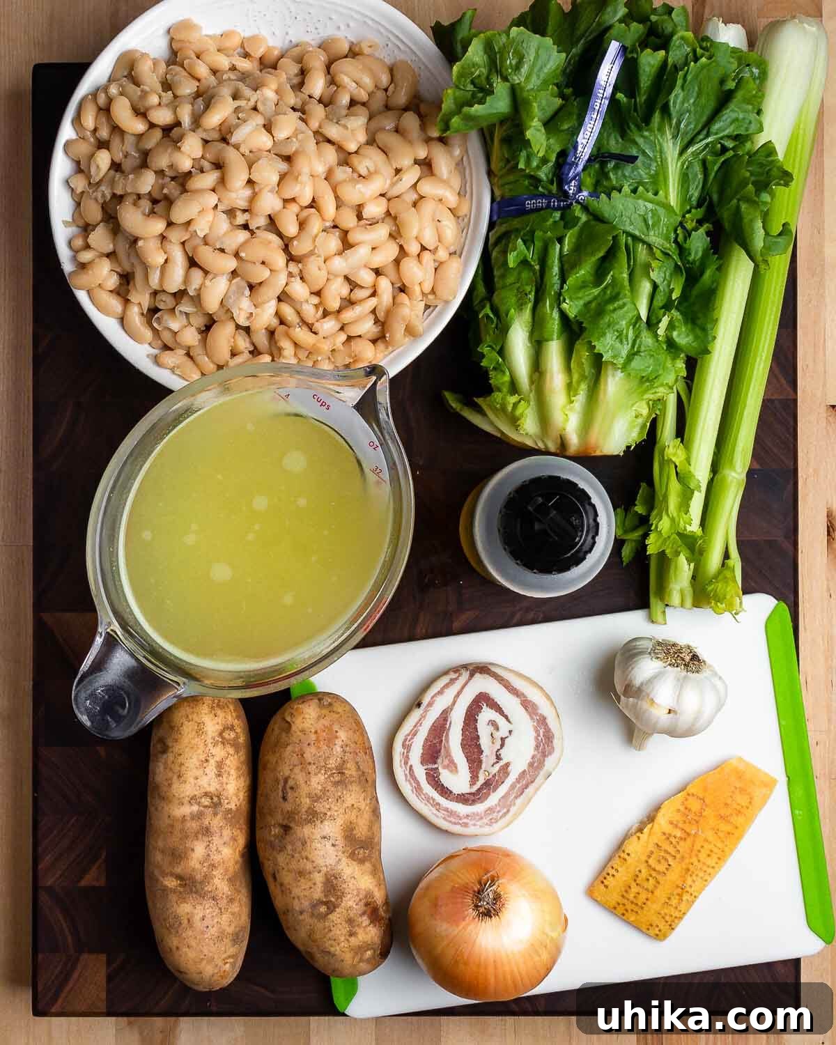 Soulful Escarole and Bean Comfort 3 A vibrant array of fresh ingredients for escarole and white bean soup, including cannellini beans, crisp escarole, chopped celery, rich chicken stock, golden olive oil, firm potatoes, savory pancetta, a pungent onion, aromatic garlic, and a savory Parmigiano rind.