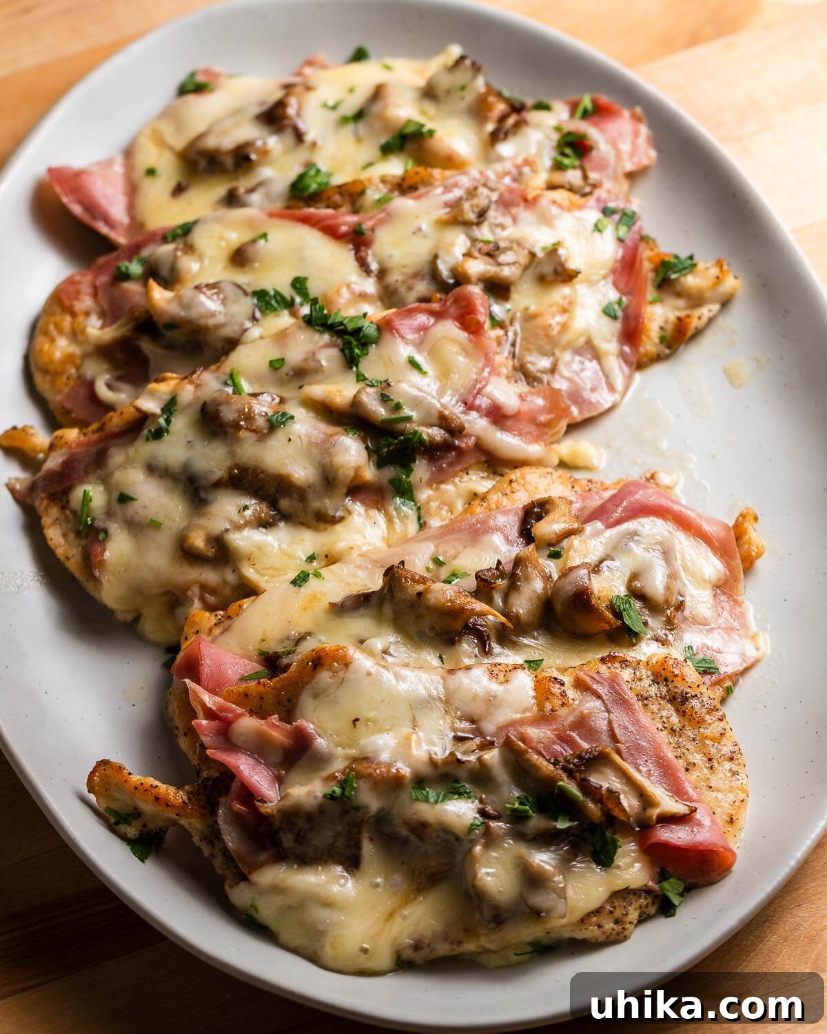 Classic Chicken Valdostana 2 A large platter of beautifully arranged Chicken Valdostana, featuring golden-brown chicken cutlets topped with melted Fontina cheese, crispy prosciutto, and sautéed mushrooms, all coated in a rich white wine sauce. Garnished with fresh parsley.