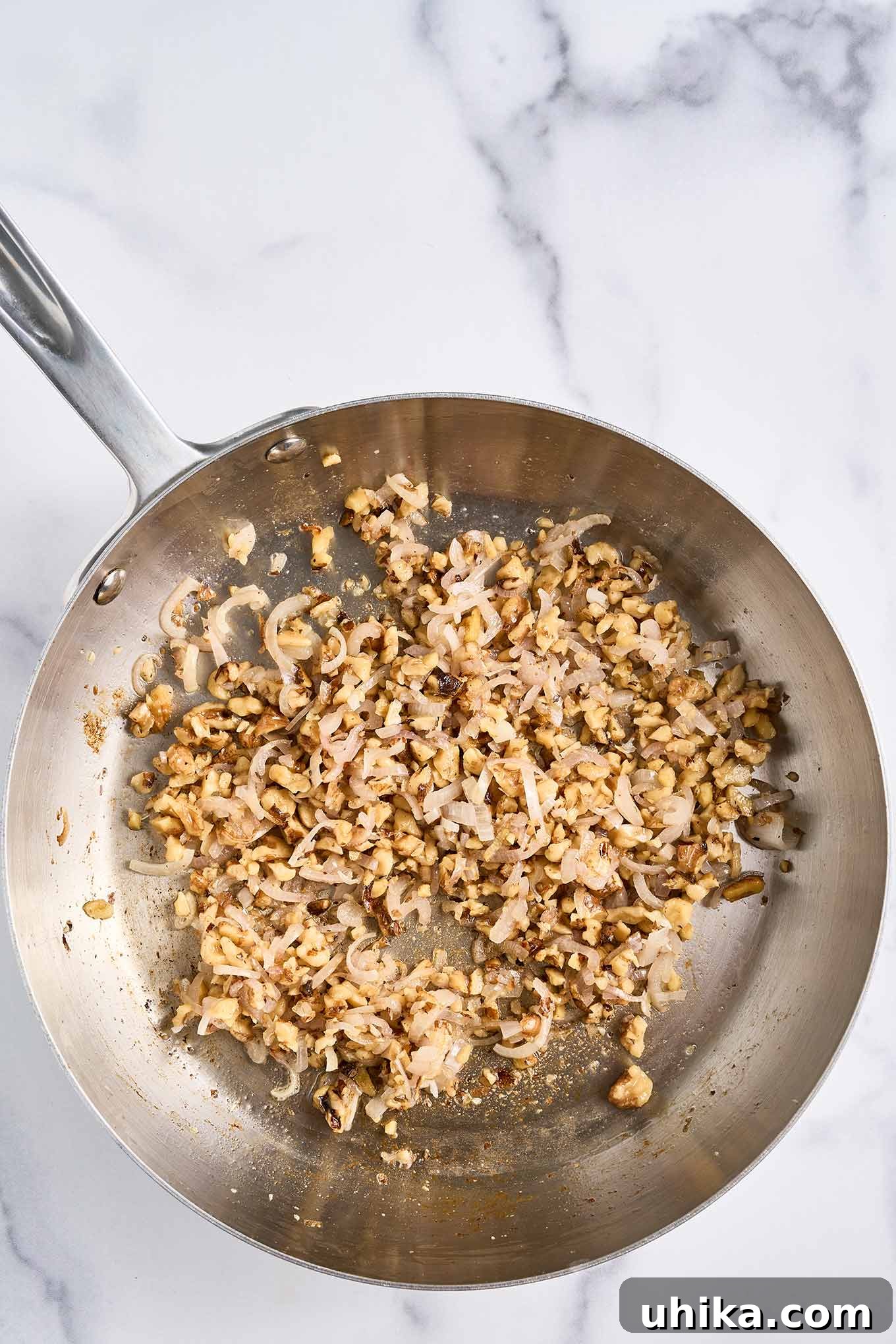 Crunchy Roasted Green Beans with Toasted Walnuts 4 Sautéed chopped walnuts and thinly sliced shallots cooking in melted butter in a stainless steel skillet, releasing their aroma.