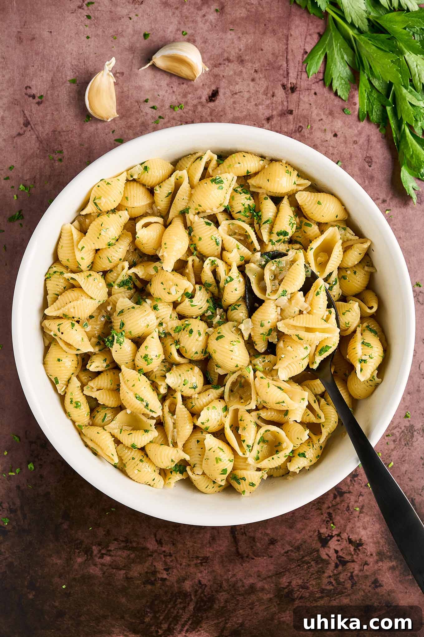 Buttery Garlic Shell Pasta 2 White bowl filled with cooked pasta shells tossed in garlic butter with balsamic vinegar, garnished with chopped parsley. A perfect weeknight side dish.