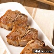 A close-up of a perfectly cooked pan-seared lamb chop, glistening with juices.