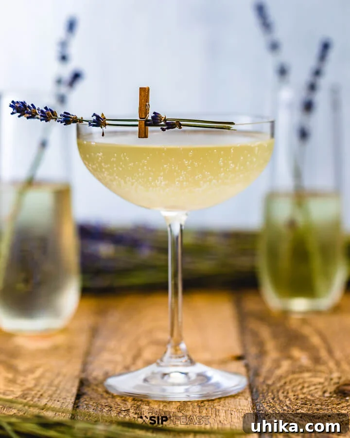 Cocktail Flutes with Lavender French 75 Three Champagne flutes, one filled with a Lavender French 75, with fresh lavender sprigs and lemons scattered on a rustic wooden table.