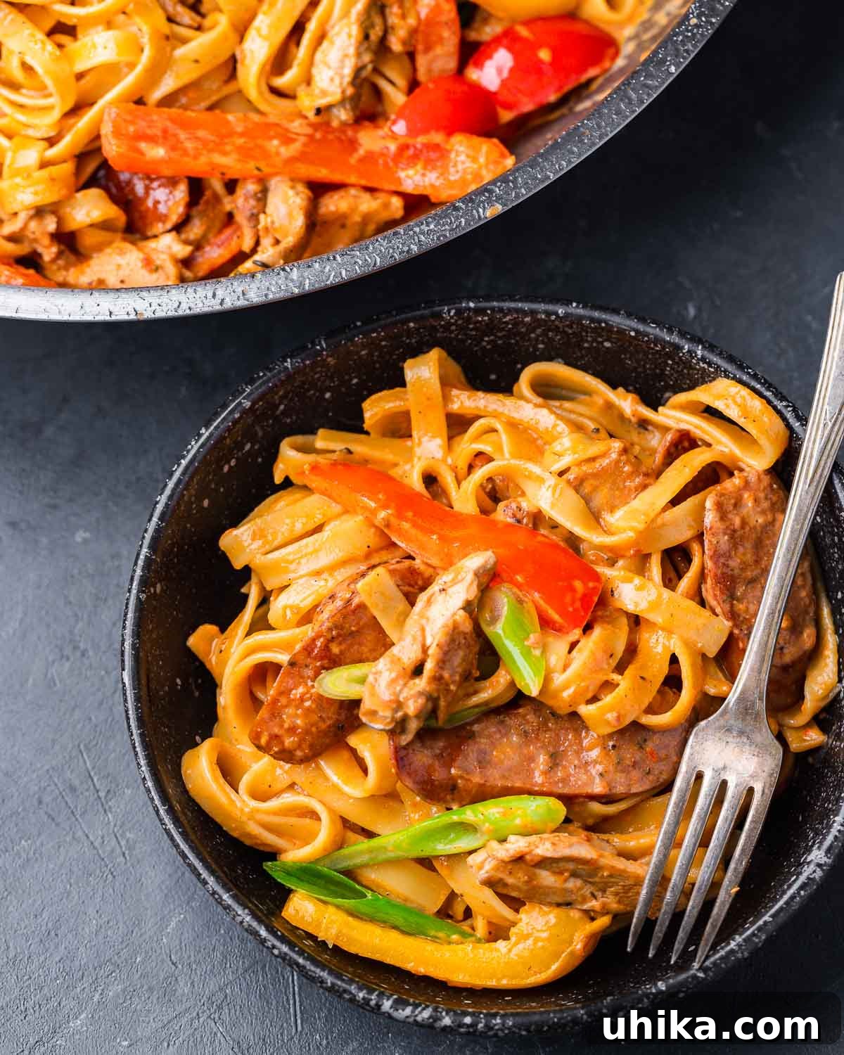 Spicy Creamy Cajun Chicken Pasta 7 Black bowl filled with creamy Cajun chicken pasta, garnished with green onions.