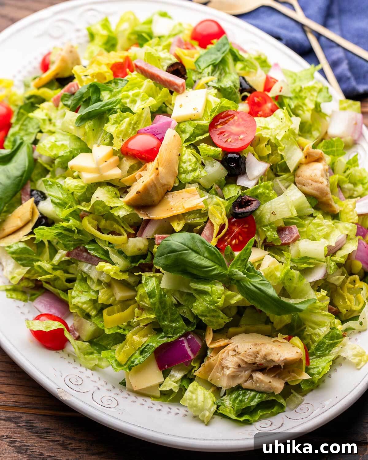 Italian Antipasto Chopped Salad 2 Vibrant Italian chopped salad with romaine, tomatoes, olives, provolone, and salami served on a white platter, ready to be enjoyed.