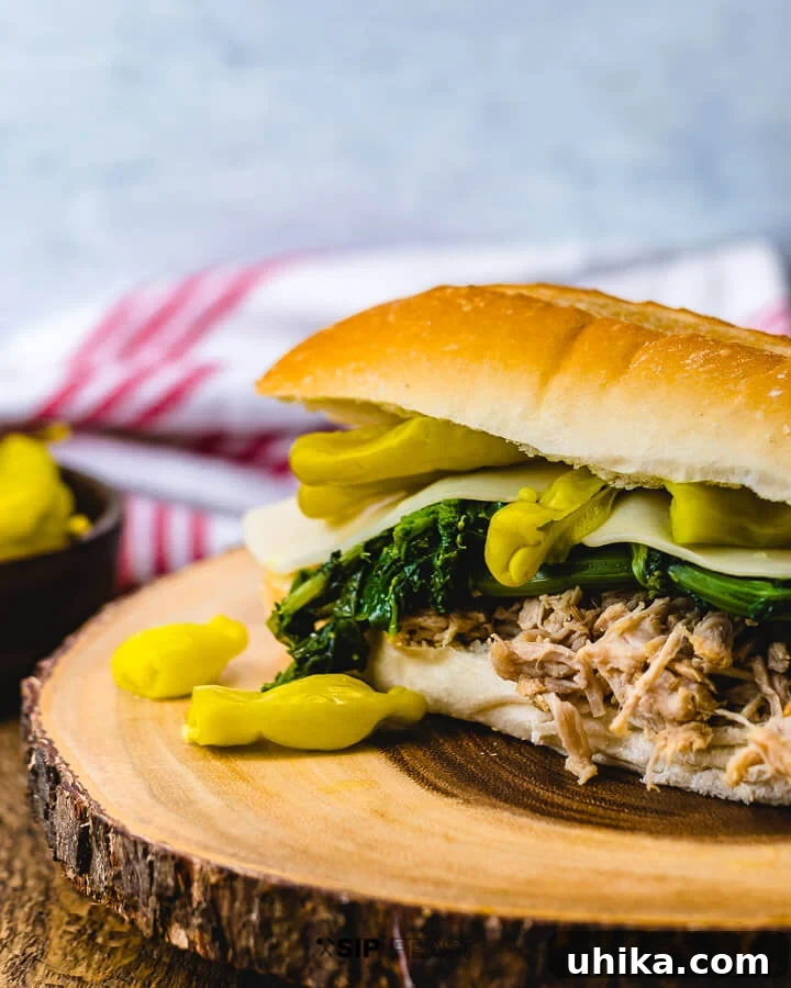 Sandwich with pulled Italian pork, broccoli rabe, provolone and Tuscan peppers on wood table. A delectable Instant Pot Italian Pulled Pork sandwich.