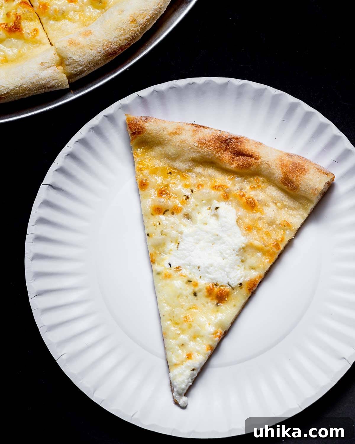 Creamy Garlic New York White Pizza 3 A perfectly baked slice of New York white pizza on a simple white plate, ready to be enjoyed.