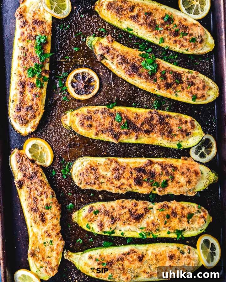 Creamy Ricotta Stuffed Zucchini 2 Overhead shot of perfectly golden-brown Lemon Ricotta Stuffed Zucchini Boats arranged neatly in a baking sheet, garnished with fresh parsley and lemon slices.