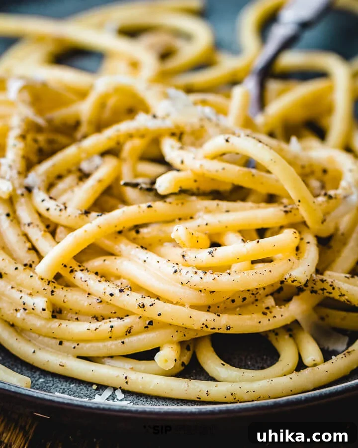 Delicious Bucatini Cacio E Pepe Served - Italian Comfort Food A close-up shot of creamy Bucatini Cacio e Pepe served on a white plate, ready to be enjoyed.