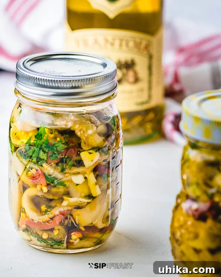 Homemade Italian Pickled Eggplant - A Classic Melanzane Sott'olio Recipe for Antipasto Jar of homemade Italian pickled eggplant glistening with olive oil, with an olive oil container in the background, ready to be served or stored.