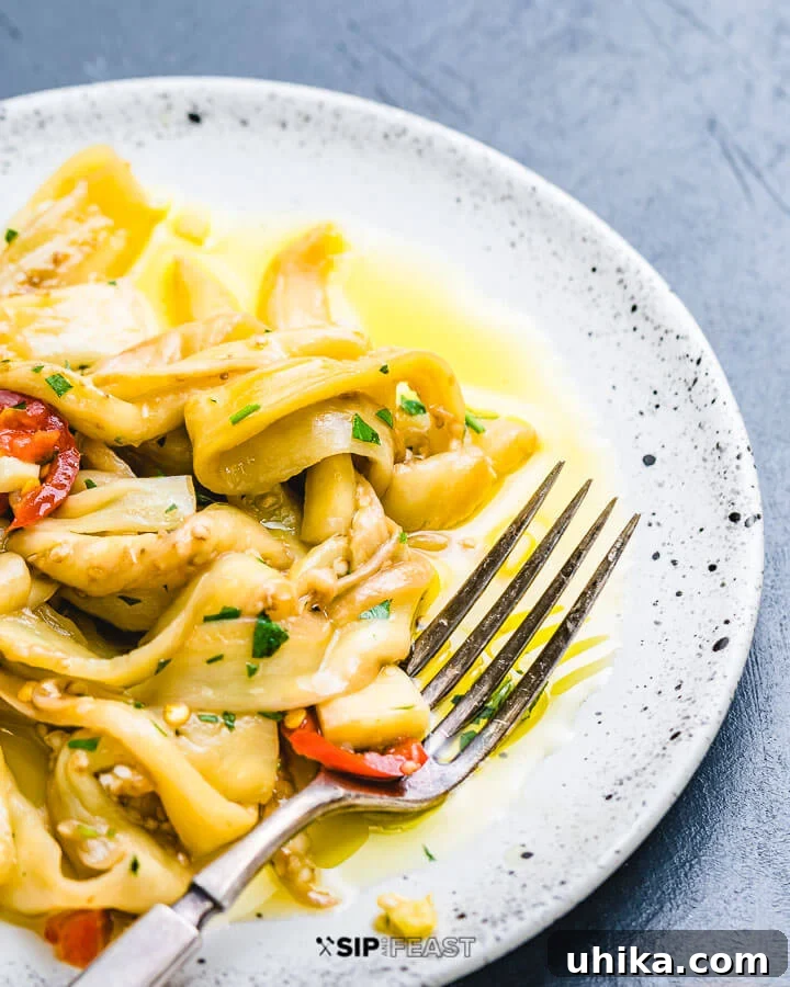 Serving Homemade Italian Pickled Eggplant with Crusty Bread White serving dish filled with perfectly pickled Italian eggplant, garnished with fresh herbs.