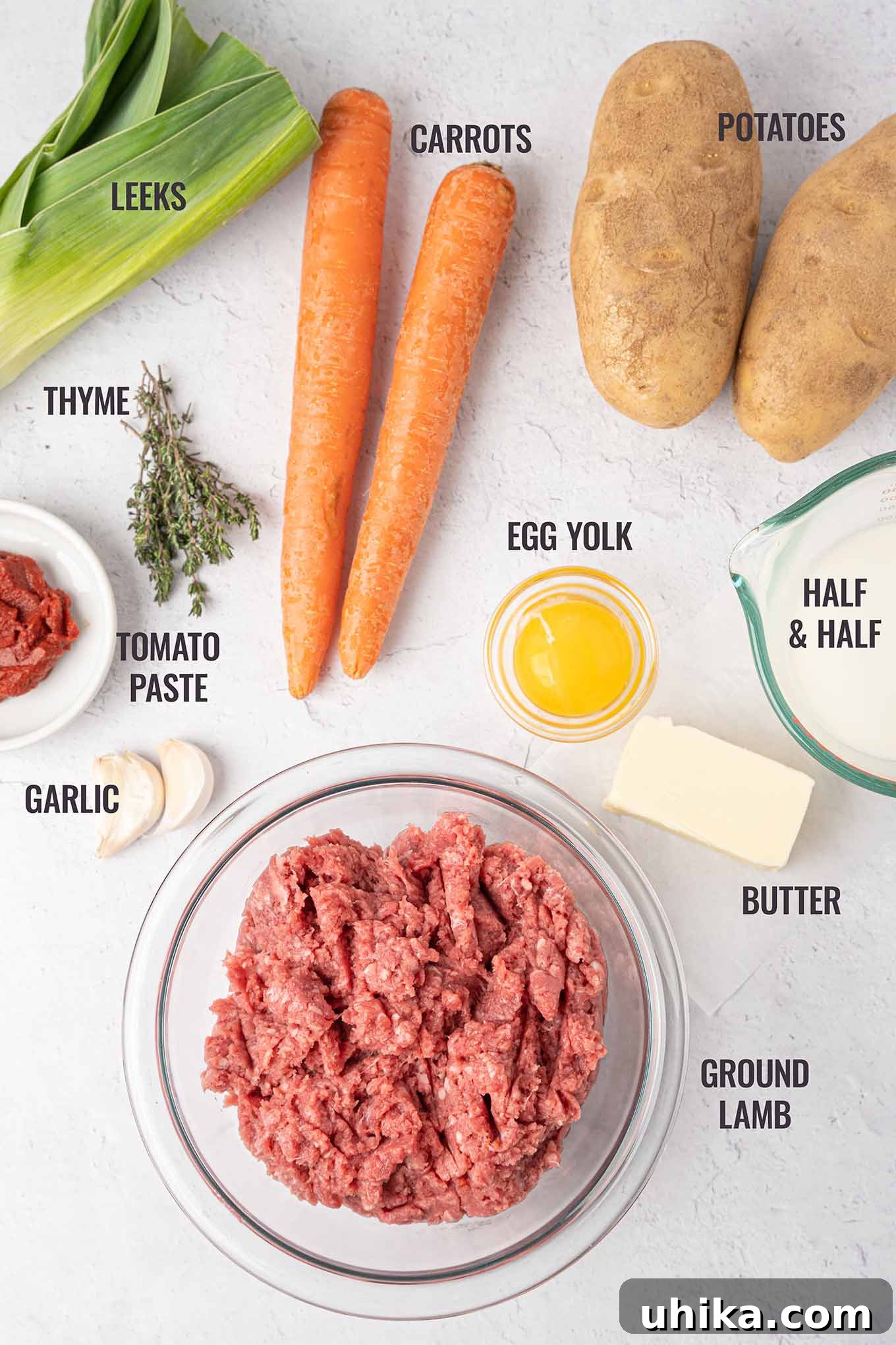 Hearty Lamb Shepherd's Pie 3 A labeled photo of Shepherd's pie ingredients including ground lamb, garlic, egg, butter, potatoes, carrots, leeks, thyme, tomato paste, and half-and-half.
