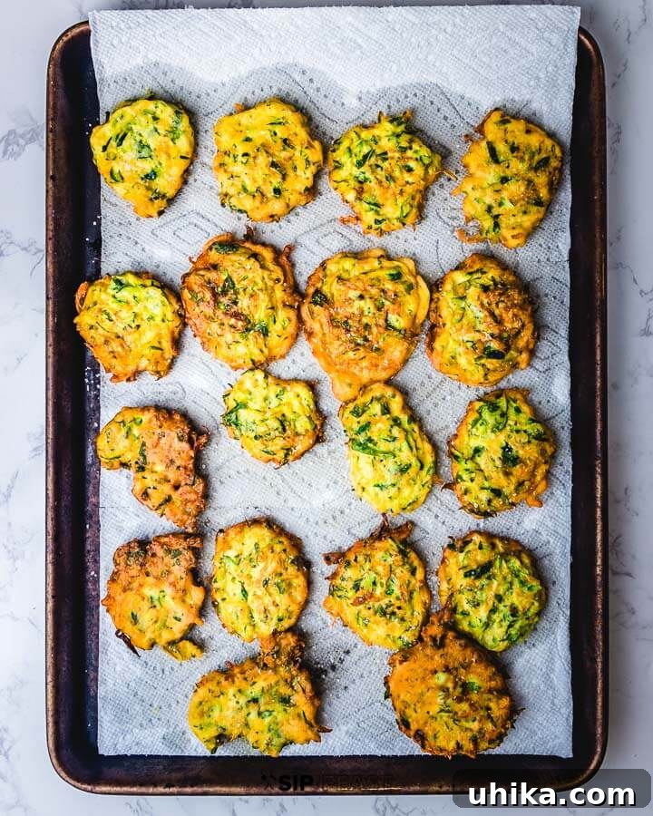 Zucchini Fritters - sipandfeast.com #zucchini #fritters #italian Sheet pan of fritters on paper towels.