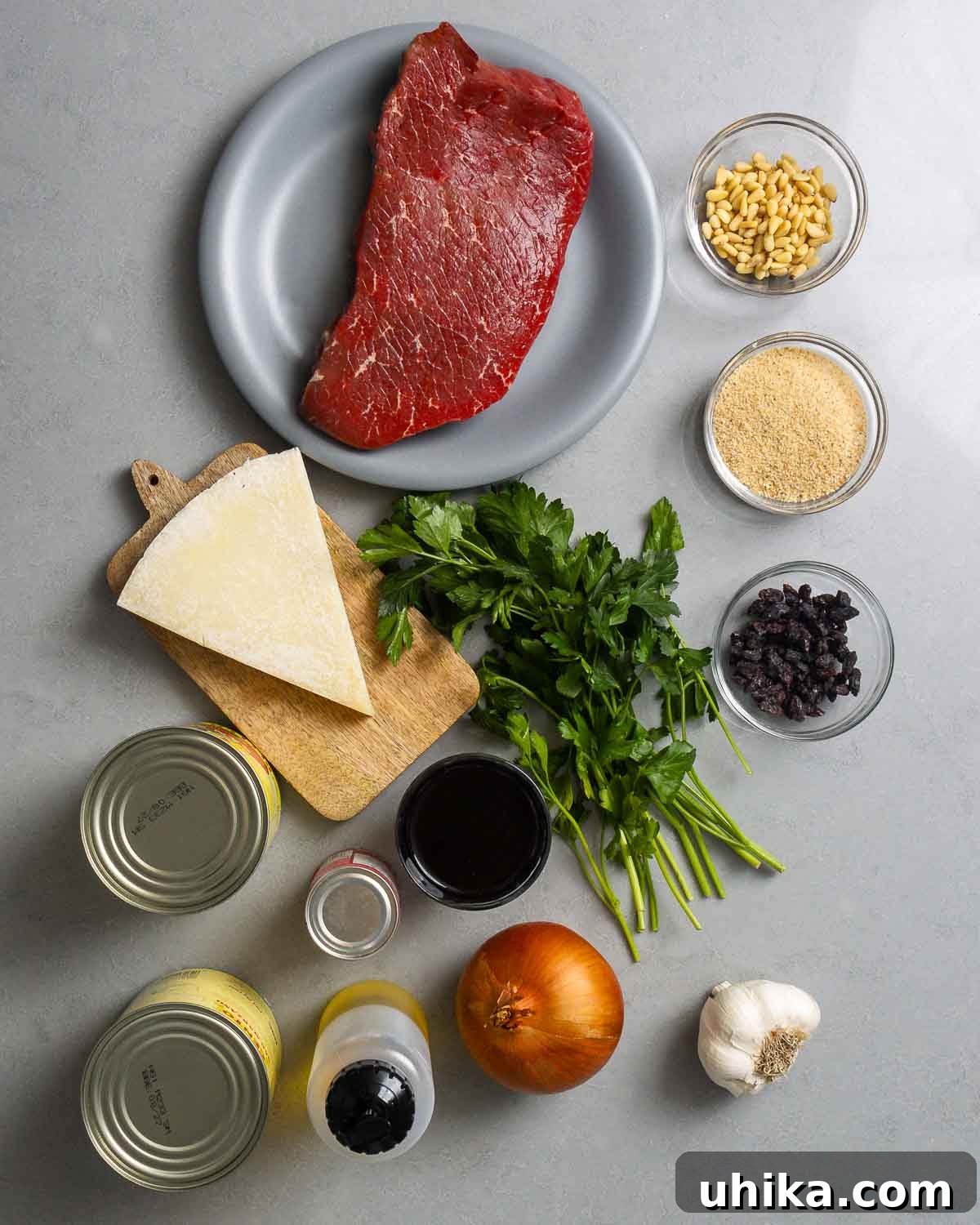 Braised Italian Beef Pinwheels 3 Ingredients shown: top round, pine nuts, breadcrumbs, raisins, Pecorino Romano, parsley, canned tomatoes, onion, red wine, olive oil, and garlic.