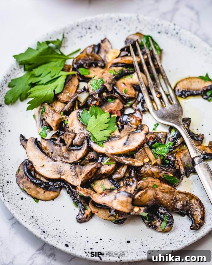Sauteed mushrooms in white plate with sprig of parsley.