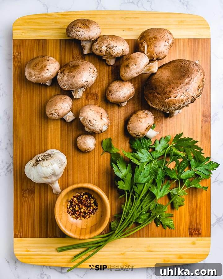 Cutting board with baby portobello mushrooms, garlic, chili flakes, and fresh parsley.