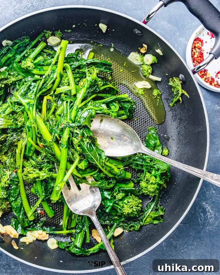 Quick Sauteed Broccoli Rabe with Garlic and Olive Oil - An Essential Italian Side Dish #broccolirabe #italianfood #sidedishrecipes Perfectly sautéed broccoli rabe with garlic in a pan, ready to be served on a rustic blue surface.