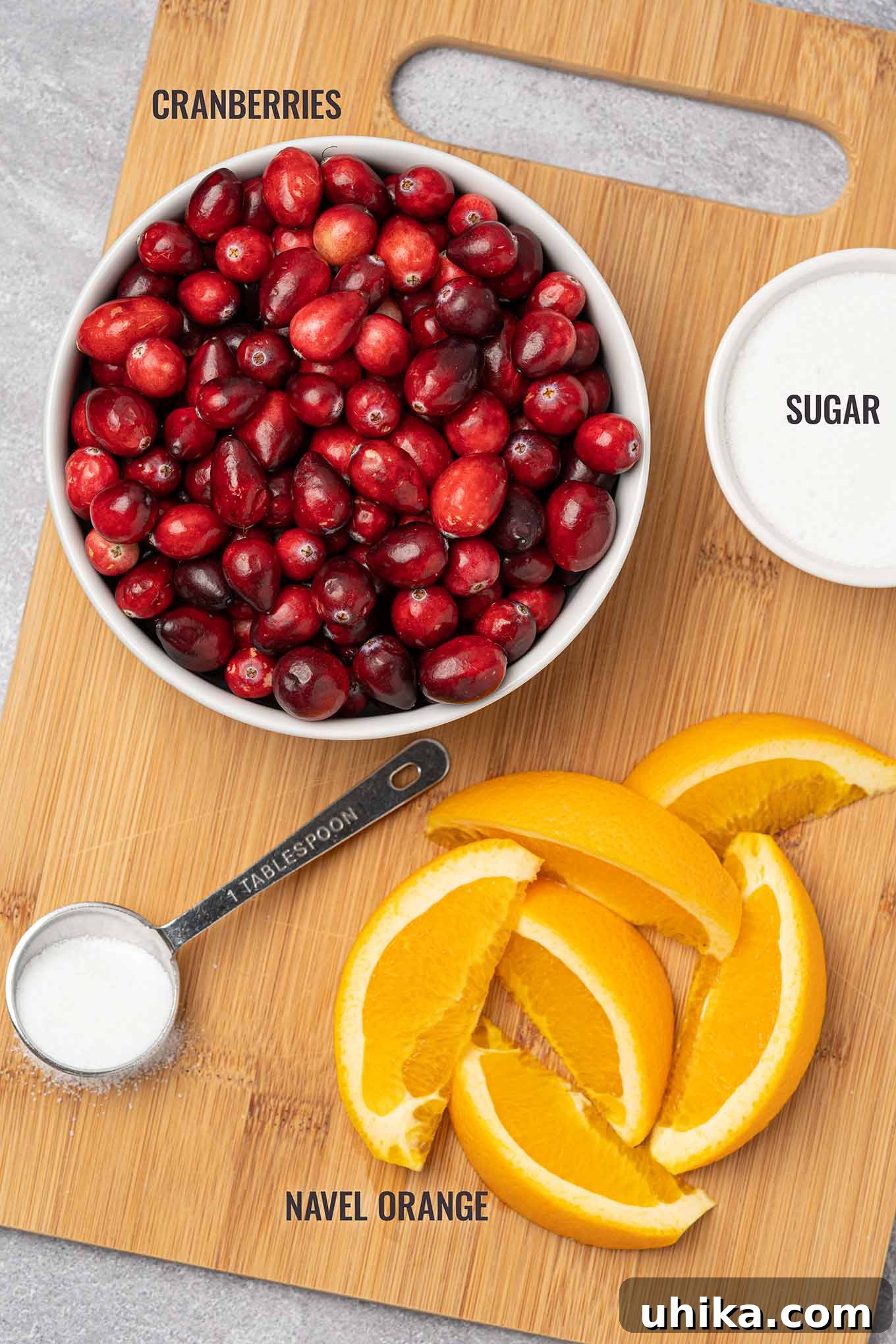 Vibrant Cranberry Orange Relish 3 A labeled, overhead view of the ingredients needed to make cranberry orange relish including fresh cranberries, sugar, and navel orange.