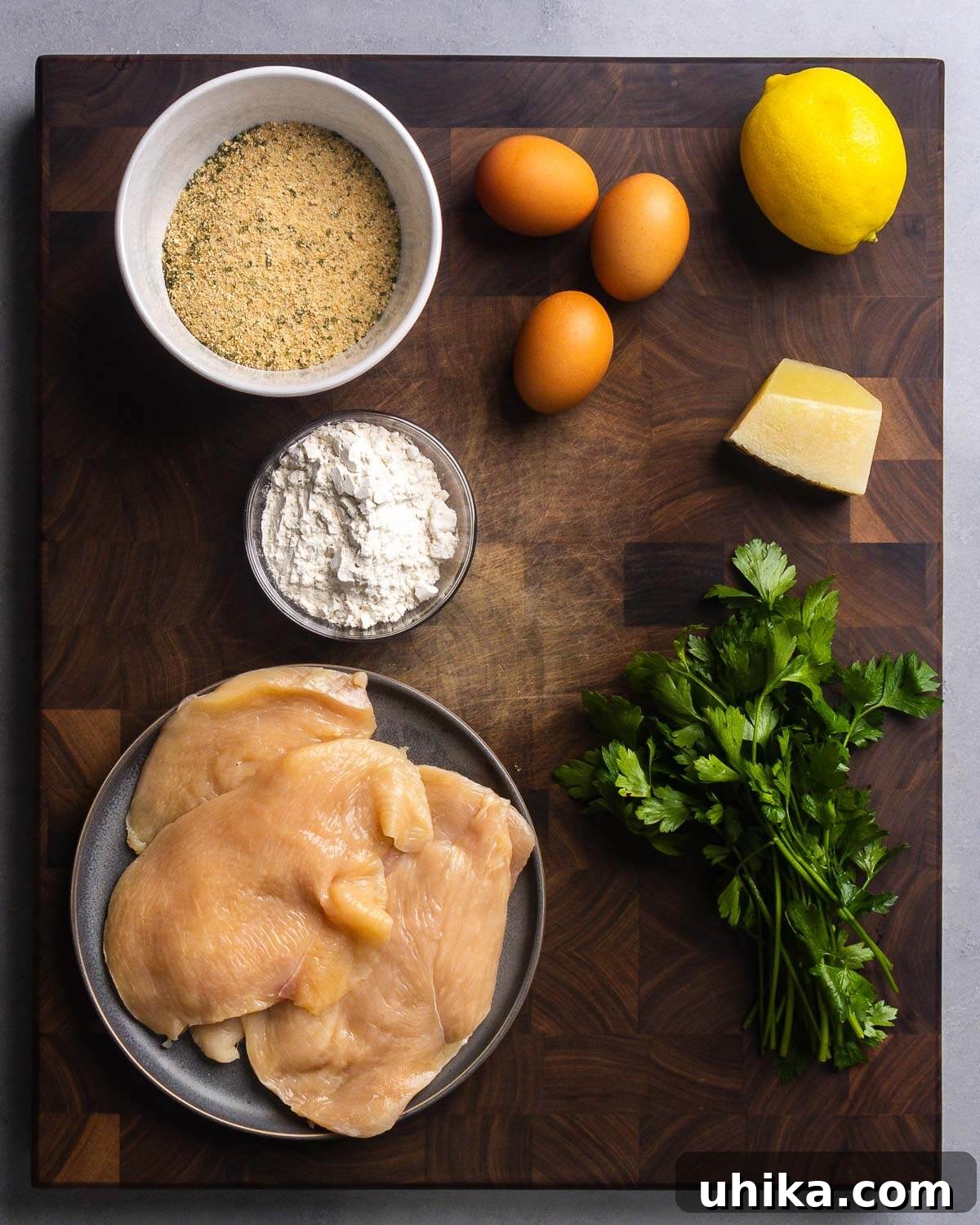 Crispy Italian Chicken Cutlets 3 Ingredients shown: seasoned breadcrumbs, eggs, lemon, flour, Pecorino Romano cheese, thinly sliced chicken cutlets, and fresh parsley.