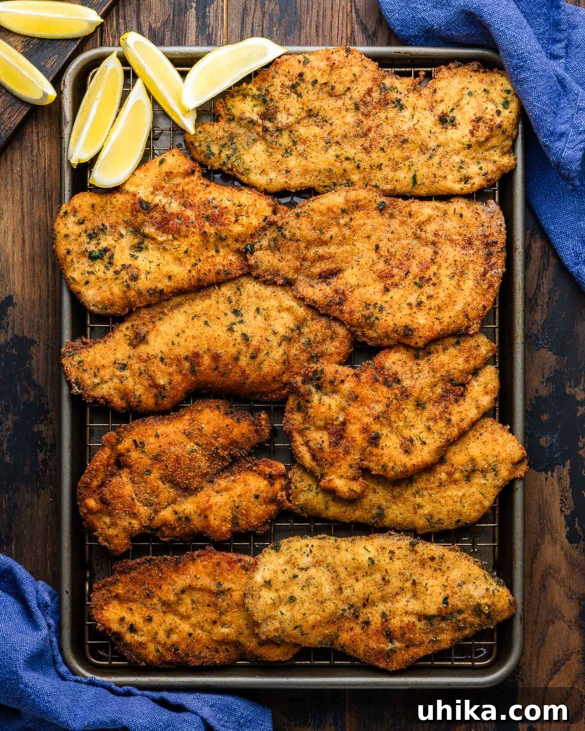 Crispy Italian Chicken Cutlets 6 Wire rack lined baking sheet with bunch of fried Italian chicken cutlets along with lemon wedges, ready to serve.