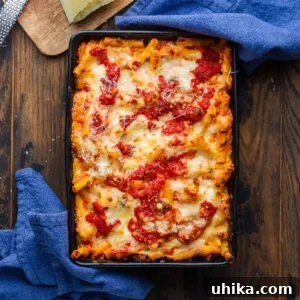Baked ziti in black baking dish with blue napkins.