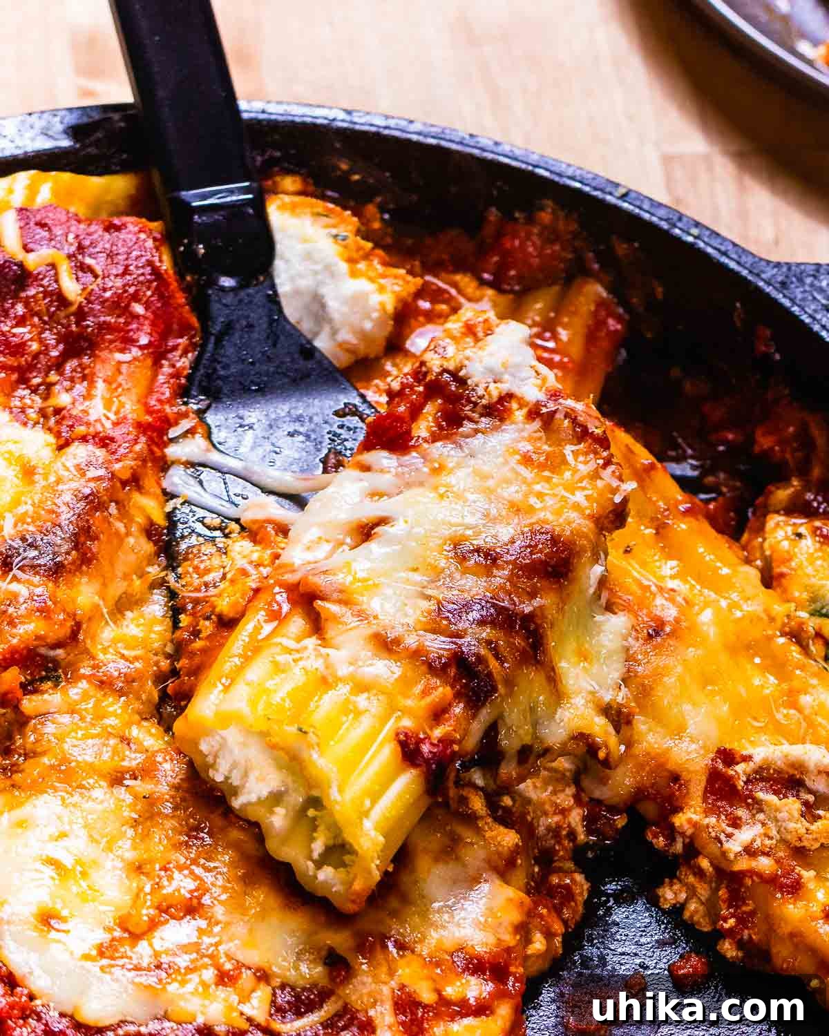 Four Cheese Baked Manicotti - The Epitome of Italian-American Comfort Food One manicotti held by a spatula, showcasing the golden-brown baked perfection.