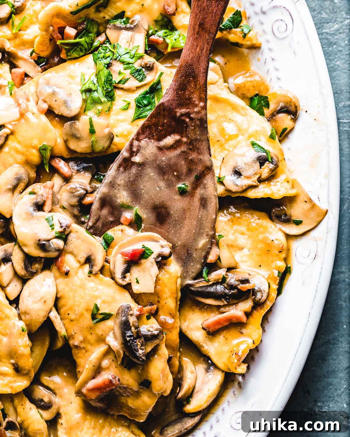 Chicken Marsala - Italian-American Comfort Food Close up shot of golden-brown chicken marsala with tender mushrooms and fresh parsley, elegantly plated on a blue background.
