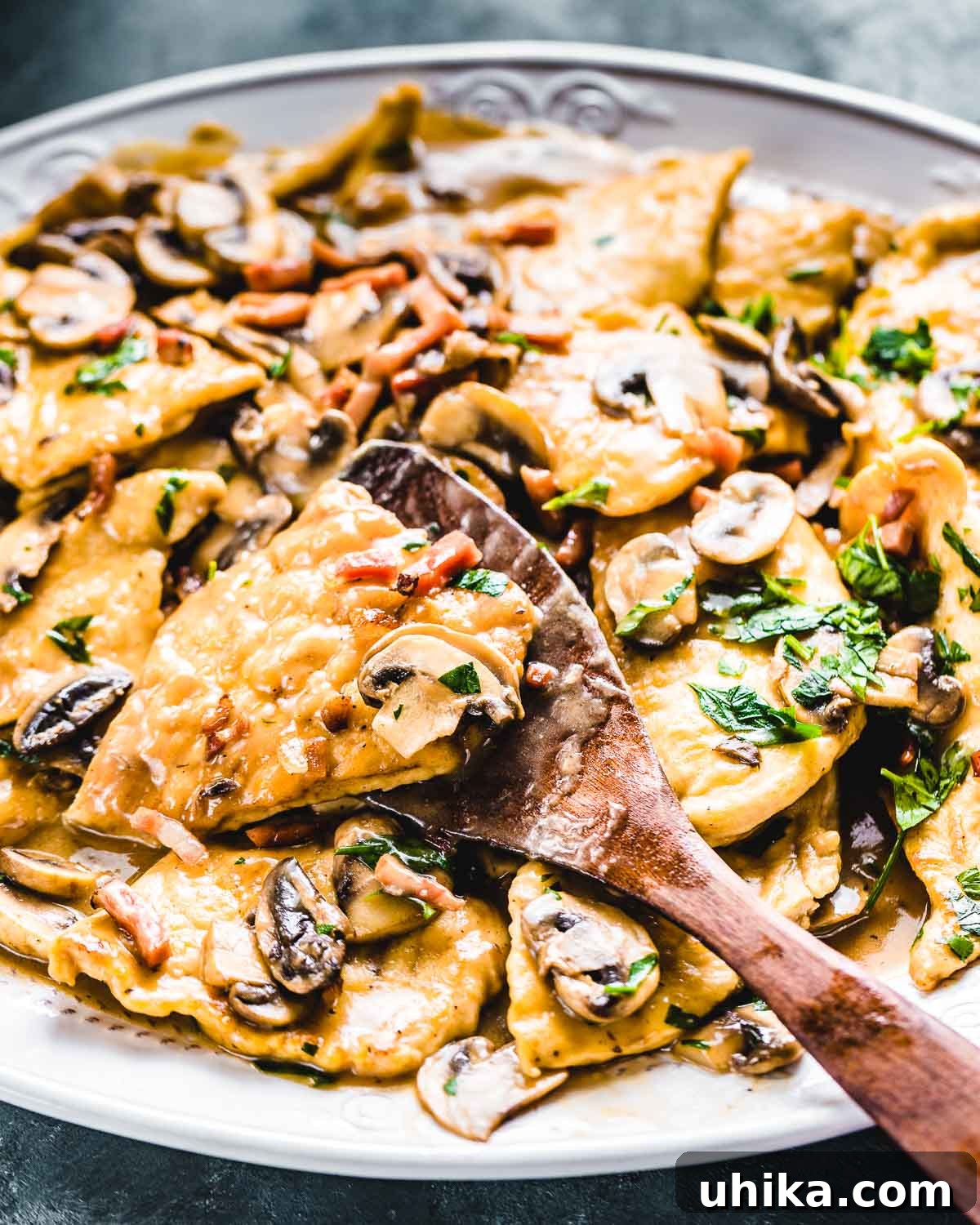 Serving Homemade Chicken Marsala A spatula gently lifting a piece of perfectly cooked Chicken Marsala over a large serving platter, showcasing its rich sauce and tender chicken.