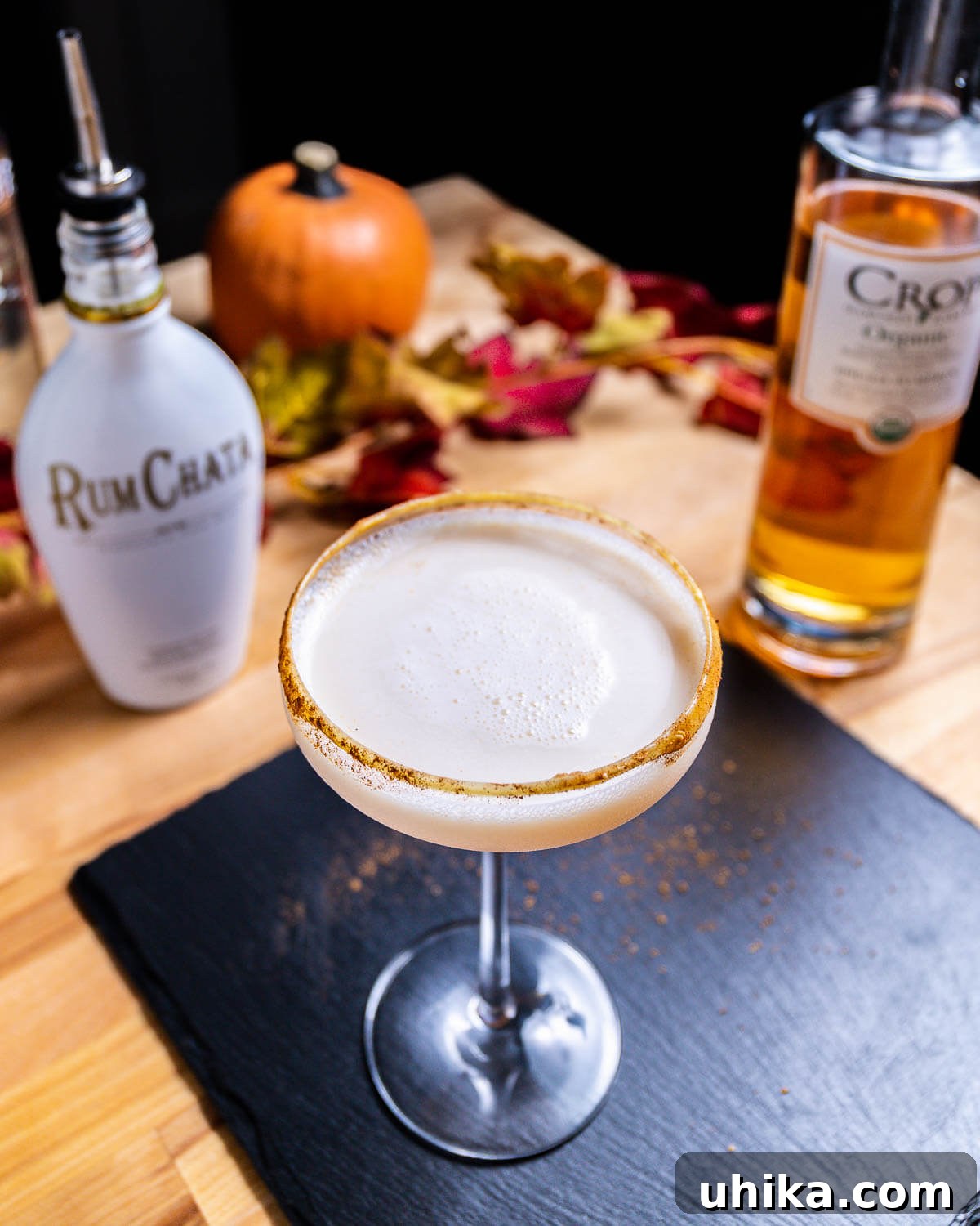 Autumn Spiced Martini 4 An elegantly served Pumpkin Spice Martini placed on a table, flanked by bottles of Rum Chata and pumpkin vodka, highlighting the complete experience.