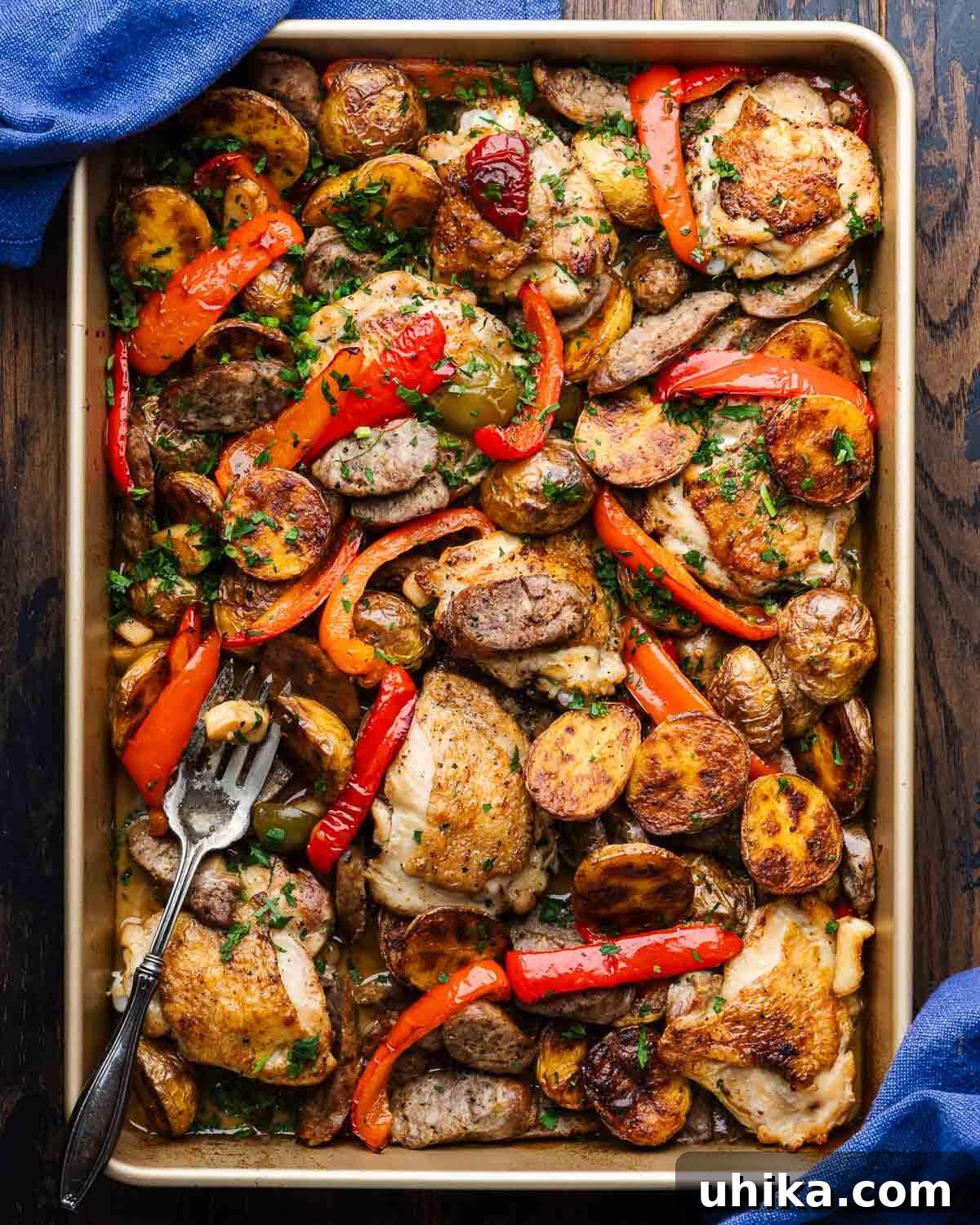 Rustic Italian Chicken and Sausage Skillet 2 Golden-brown Chicken Scarpariello with sausage, peppers, and roasted potatoes in a rustic gold baking pan, garnished with fresh parsley and ready to be served.