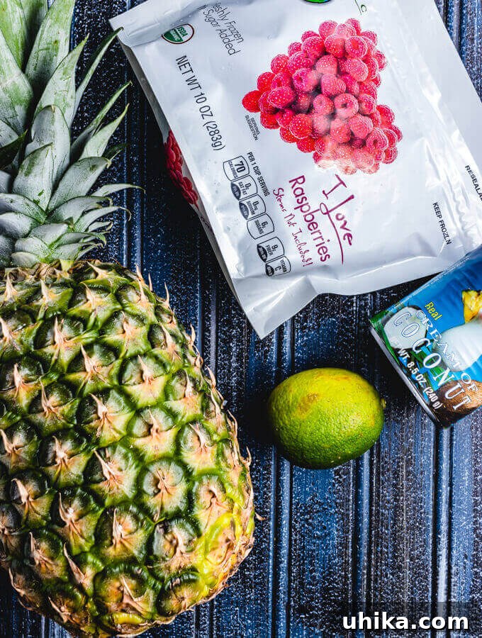 Molten Raspberry Colada 3 Essential ingredients for a Raspberry Colada Cocktail: fresh pineapple chunks, zesty lime, rich Coco Lopez Cream of Coconut, and vibrant frozen raspberries, ready for blending.