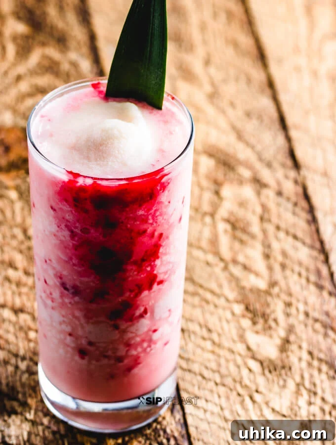 Molten Raspberry Colada 8 A stunning Raspberry Colada Cocktail in a painted glass, garnished with fresh raspberries and a pineapple wedge, ready to be enjoyed.