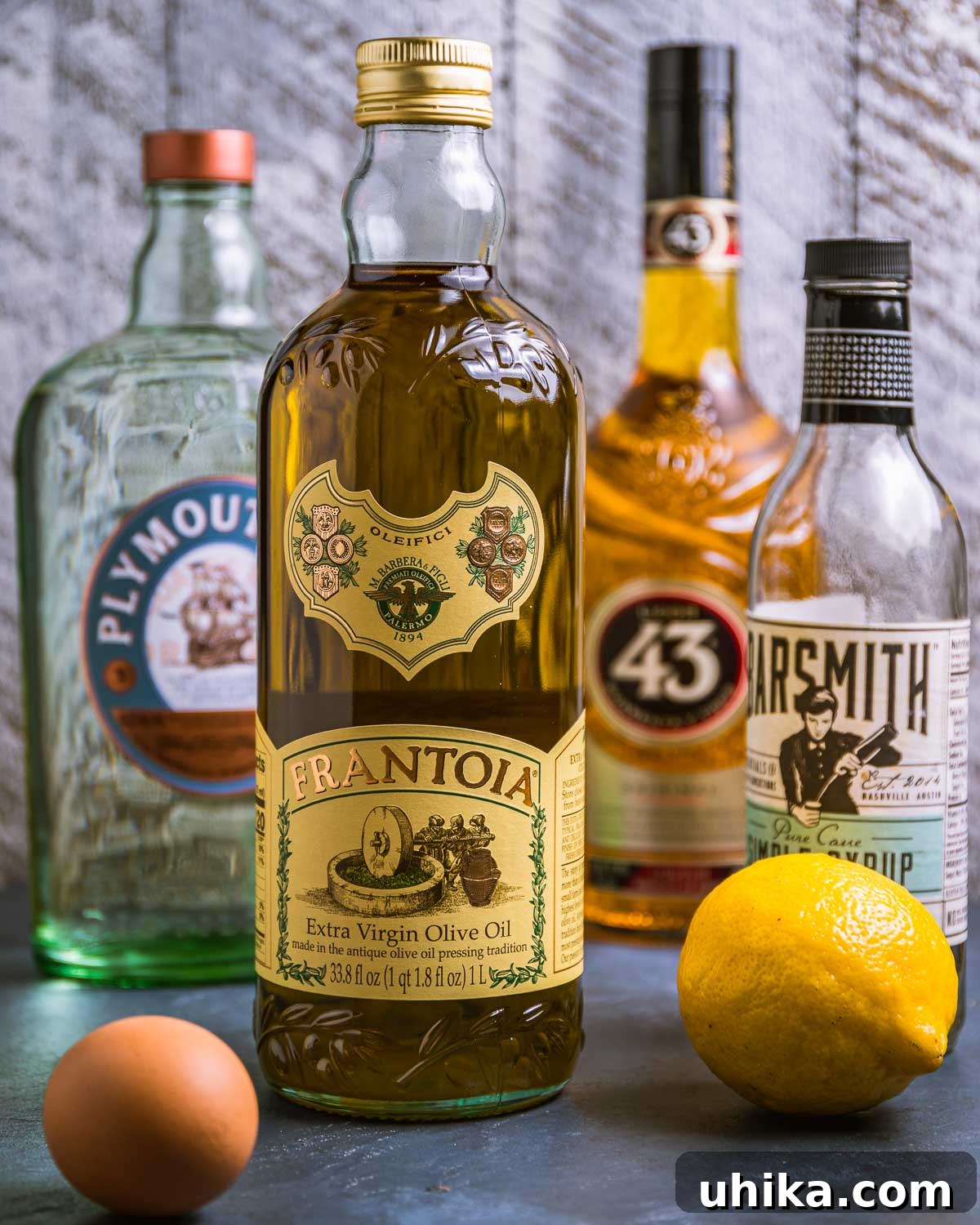 Ingredients for Oliveto cocktail shown: gin, olive oil, Licor 43, simple syrup, lemon, and egg.