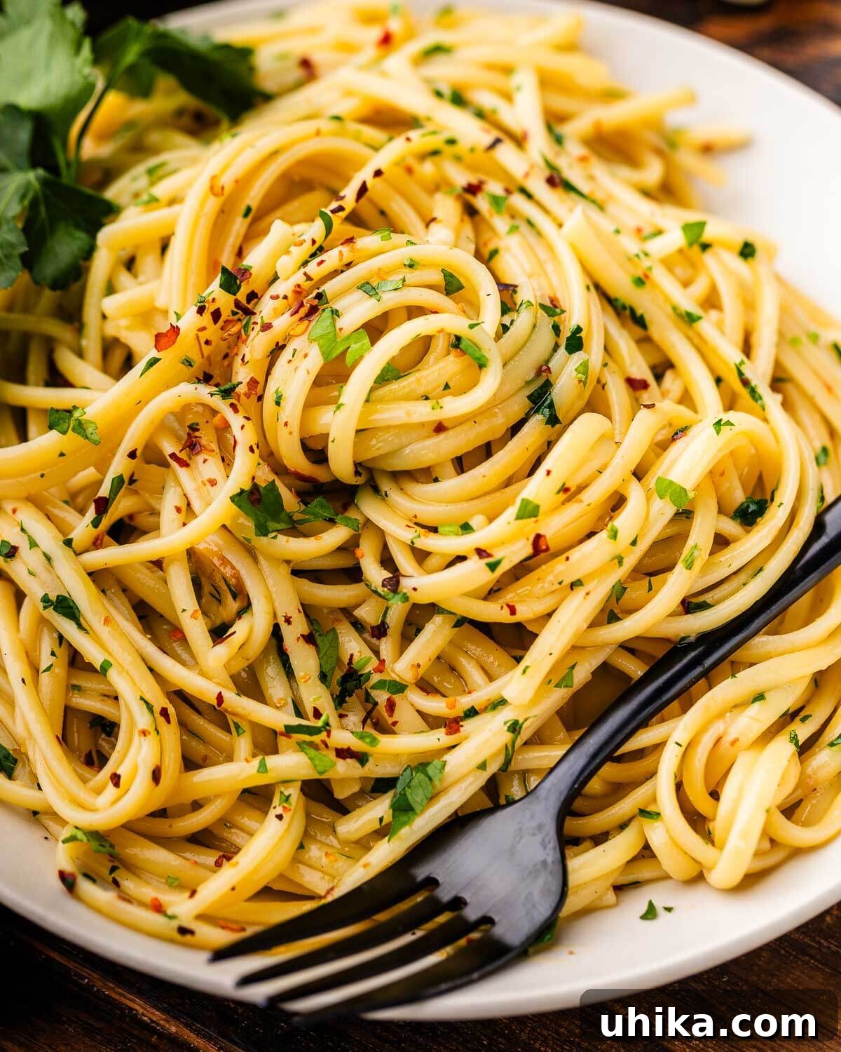 Aromatic Garlic and Olive Oil Linguine 2 Freshly prepared Linguine Aglio e Olio served in a white bowl, garnished with green parsley.