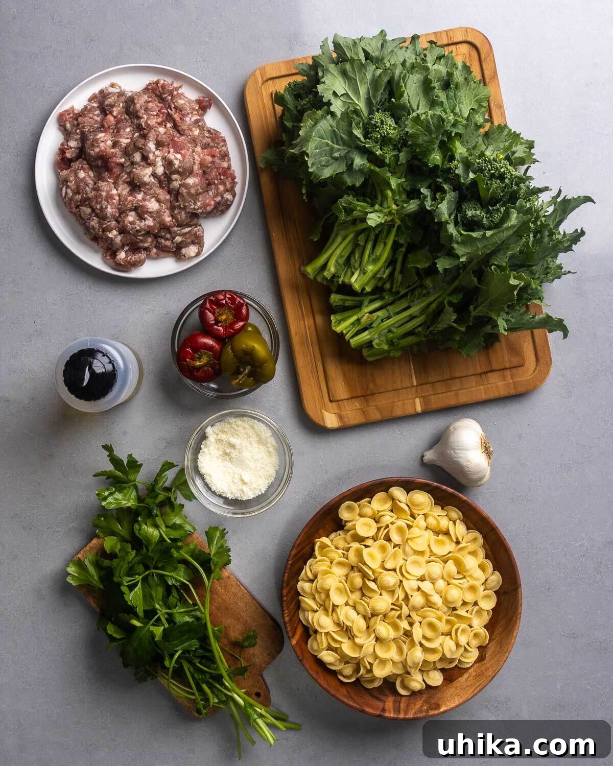 Rustic Orecchiette with Sausage and Broccoli Rabe 4 A flat lay photograph showcasing all the fresh ingredients for orecchiette with sausage and broccoli rabe: bulk Italian sausage, fresh broccoli rabe, olive oil, vibrant cherry peppers, grated Pecorino Romano cheese, fresh parsley, aromatic garlic, and orecchiette pasta.
