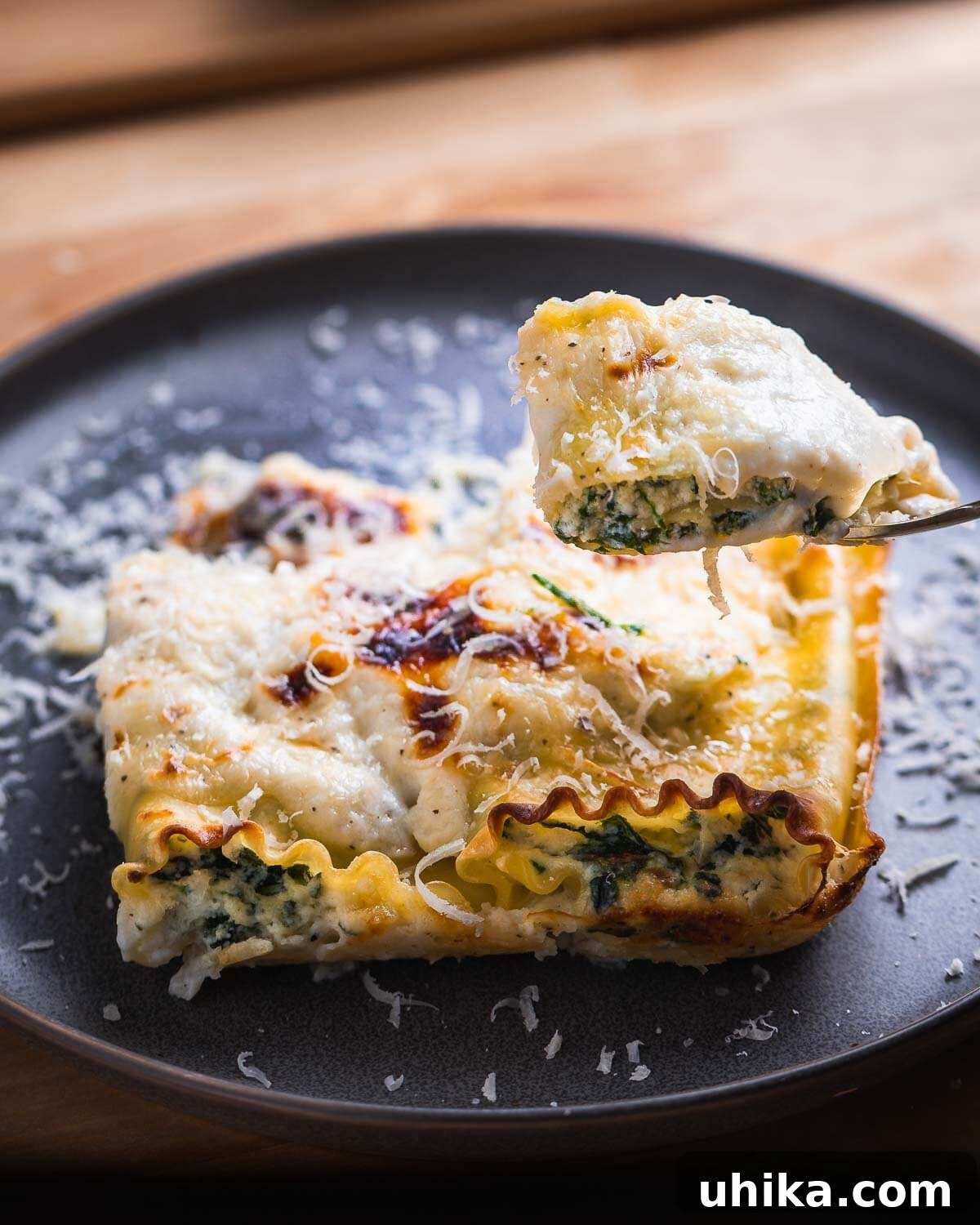 Creamy Spinach Lasagna Rolls 7 A close-up of a cut spinach lasagna roll up, held by a fork, showcasing the creamy filling and tender pasta.