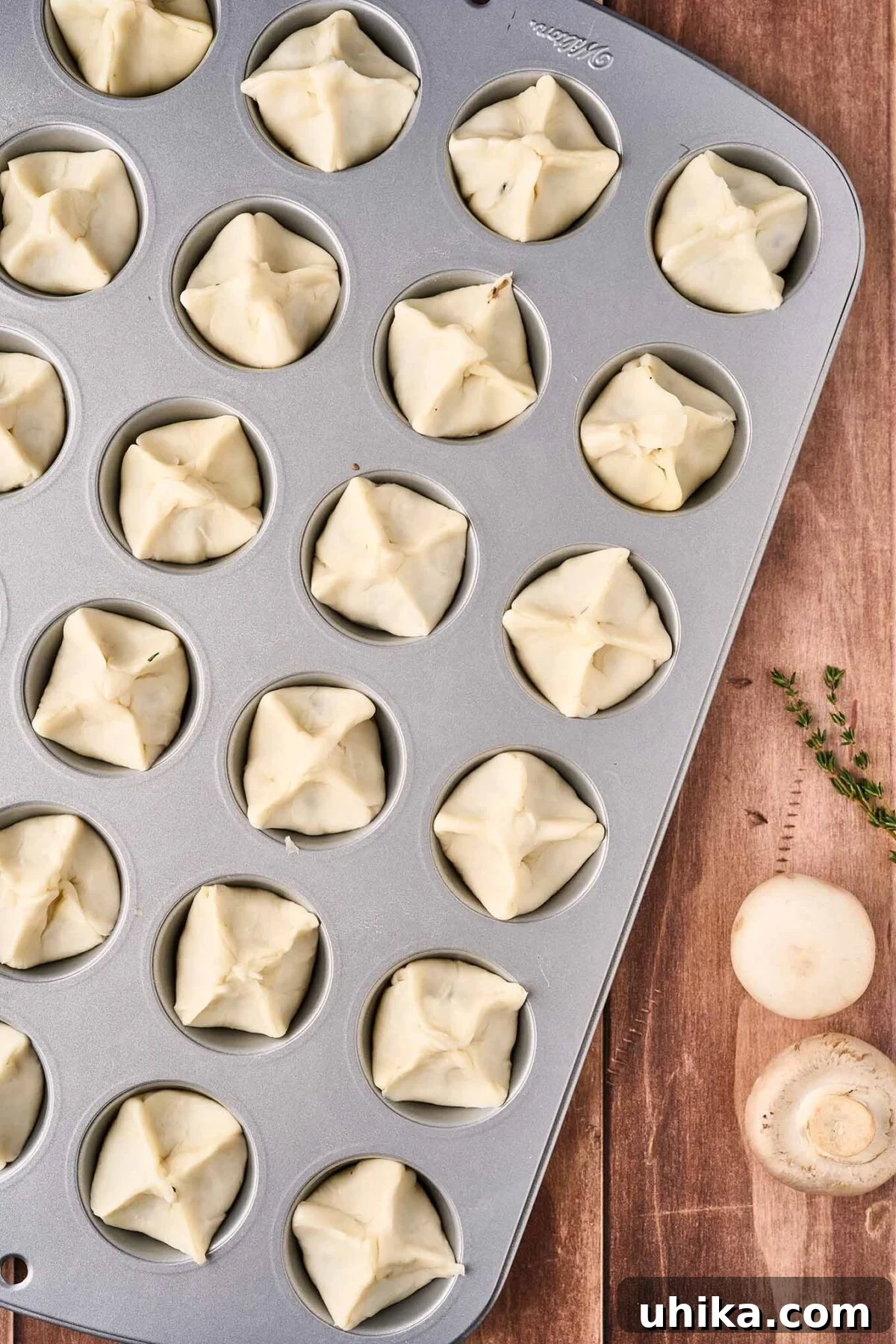 Umami Cloudlets 7 A mini muffin tin with mushroom puffs ready for the oven, demonstrating how to pinch the tops to get the proper shape once baked.