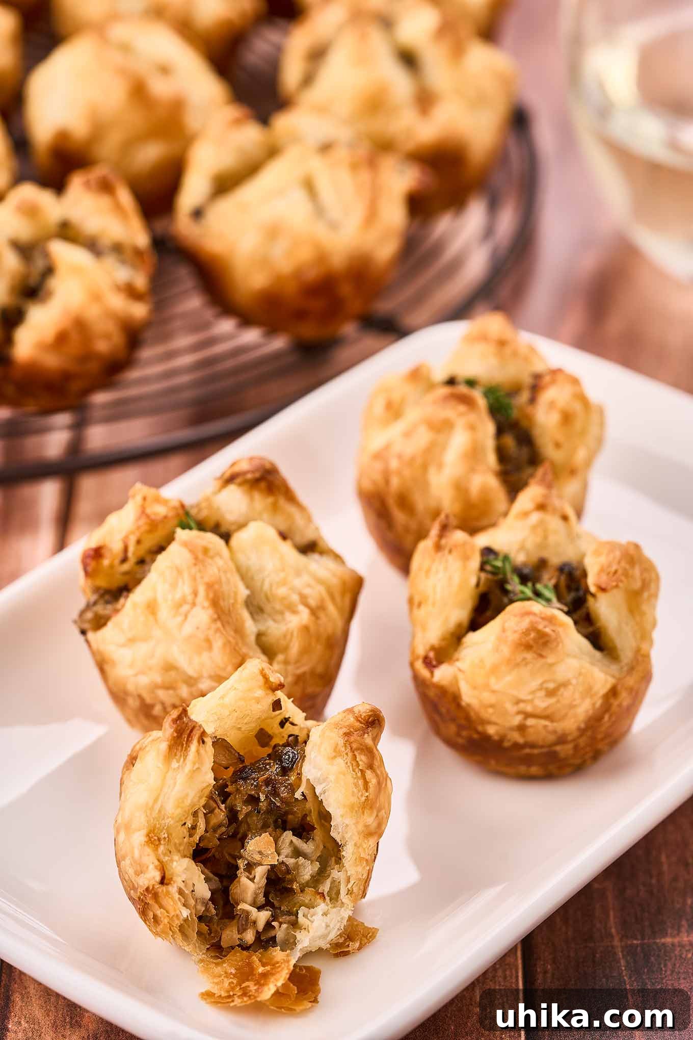 Umami Cloudlets 8 Four mushroom puff pastry appetizers on a small plate, one with a bite out of it to show the interior.