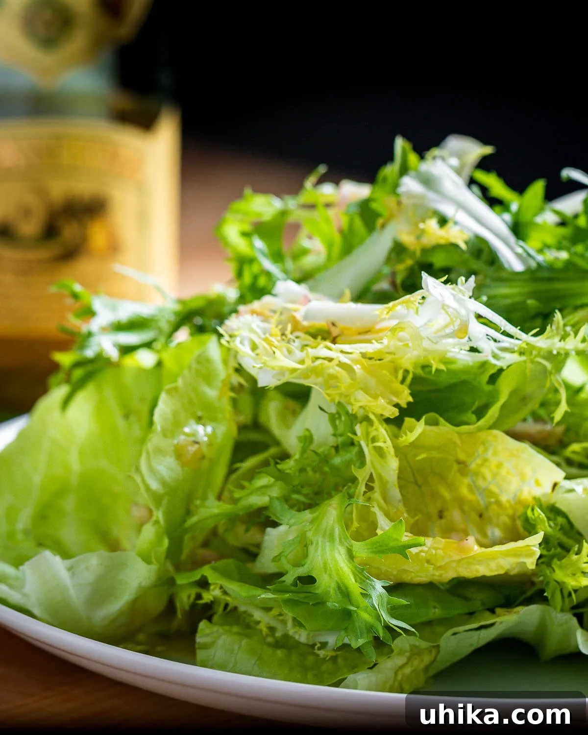 Via Carota House Salad 2 Plate of piled high lettuce greens with bottle of olive oil in background.