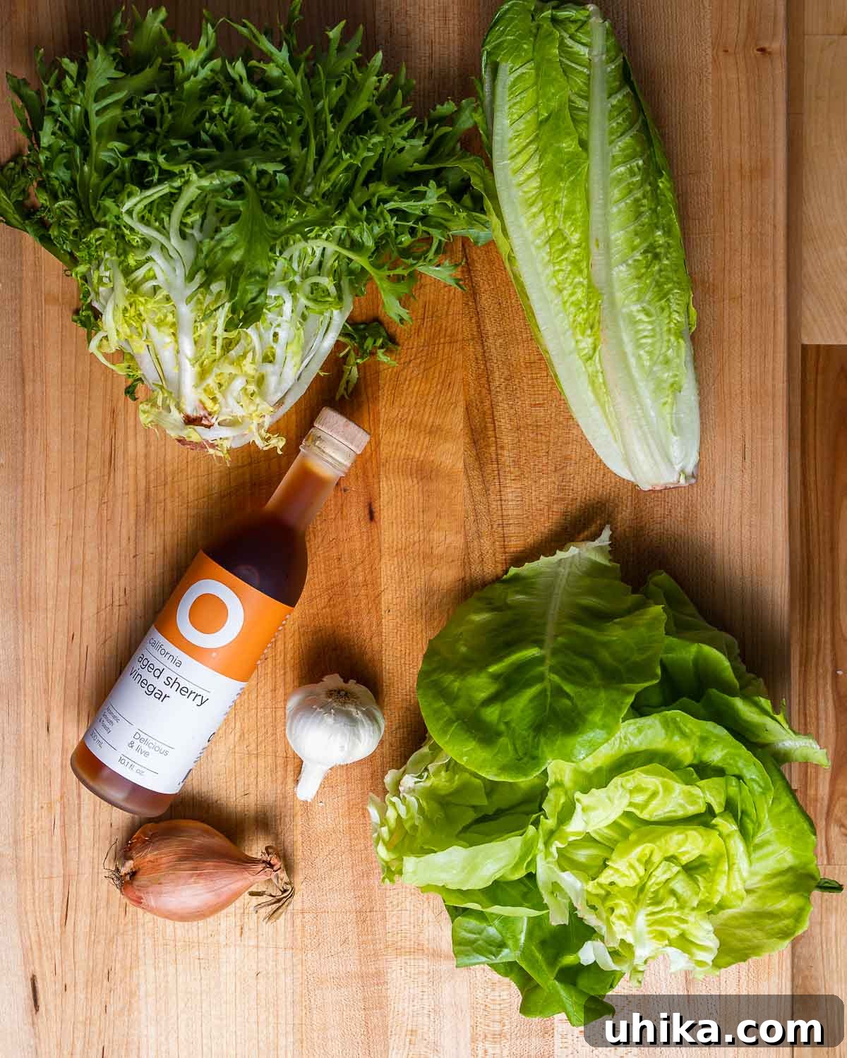 Via Carota House Salad 3 Ingredients shown: frisee, romaine, and Boston lettuce along with bottle of sherry vinegar, head of garlic, and shallot.