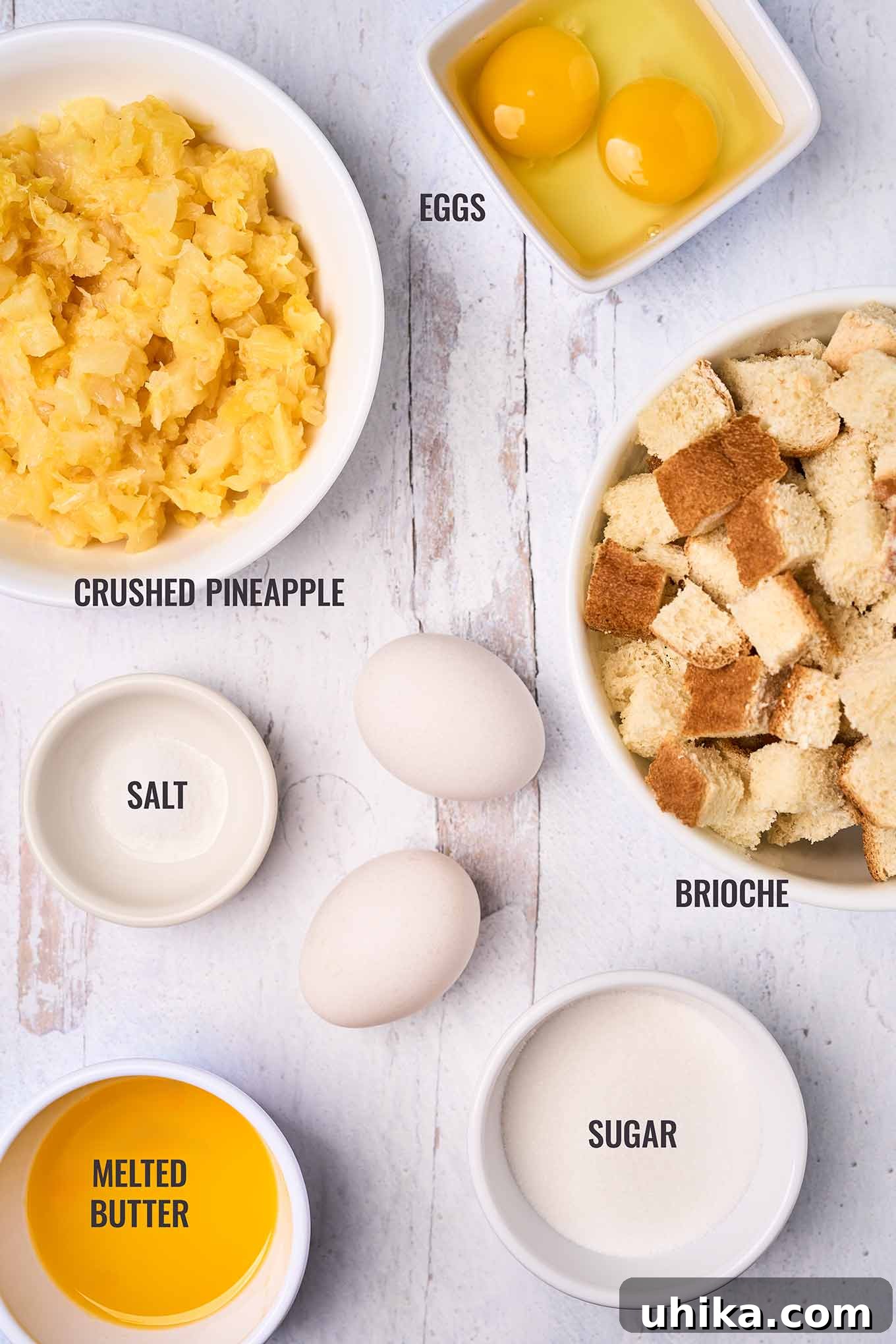 Sunshine Pineapple Bliss 3 A labeled, overhead view of scalloped pineapple ingredients including crushed pineapple, eggs, brioche bread cubes, sugar, salt, and melted butter.