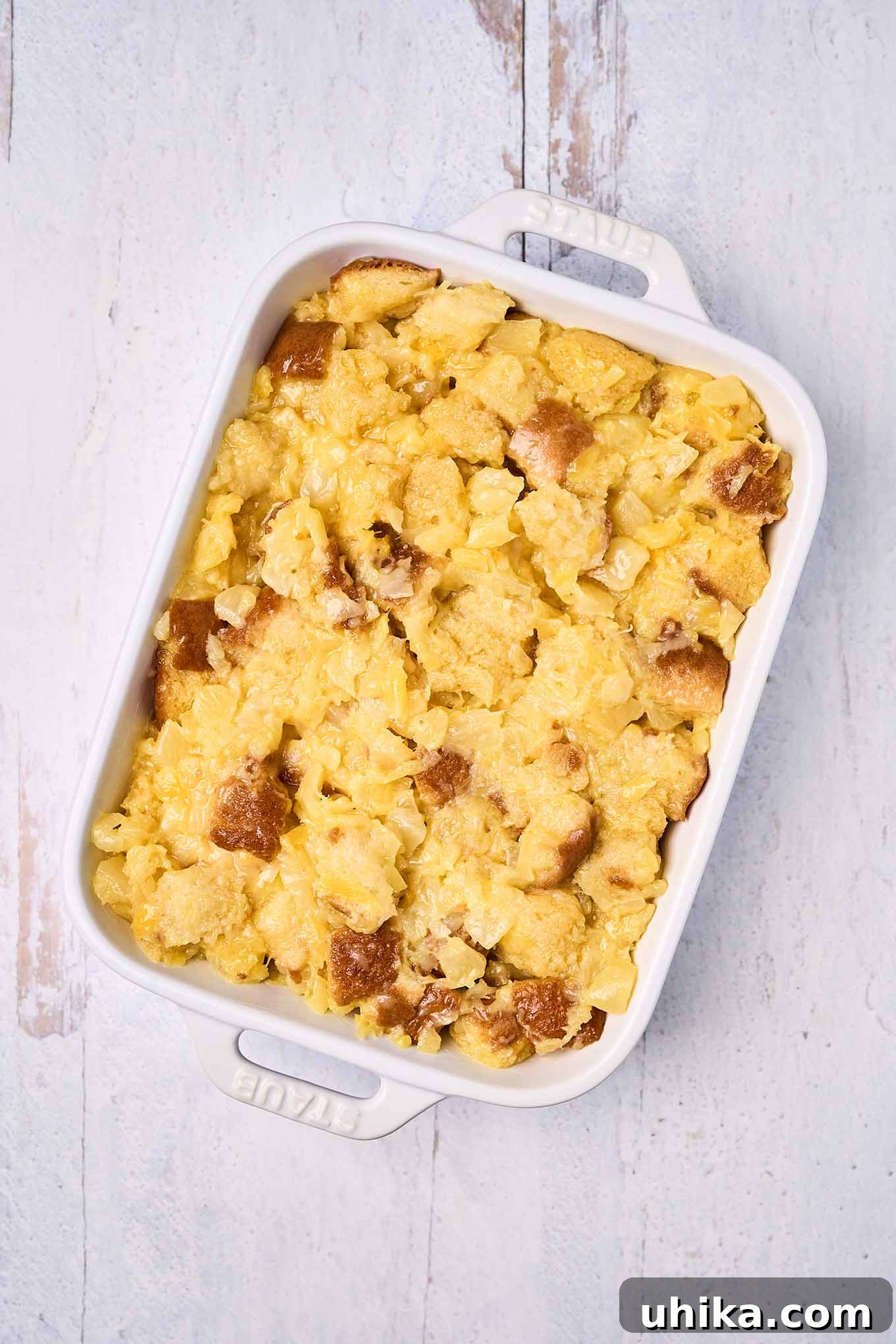 Sunshine Pineapple Bliss 5 Brioche bread, crushed pineapple, eggs, and melted butter combined and spread in a casserole dish ready for the oven.